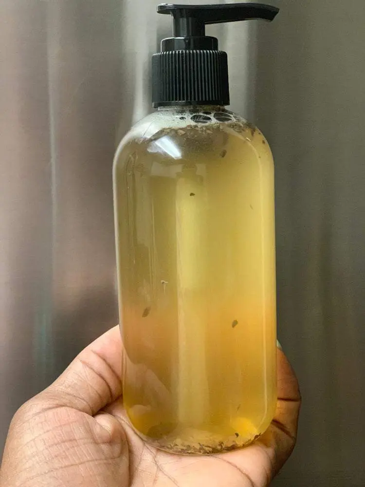 Hand holding a bottle of amber liquid soap. Hand holding a bottle of amber liquid soap.