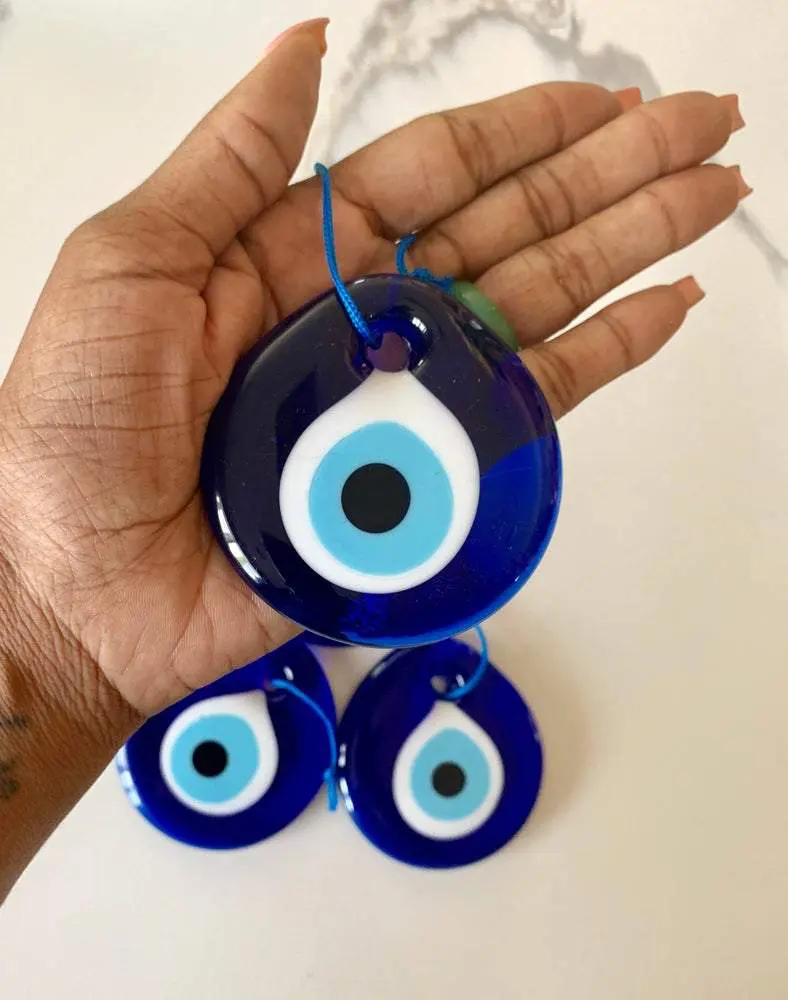 Three blue evil eye charms in hand. Three blue evil eye charms in hand.