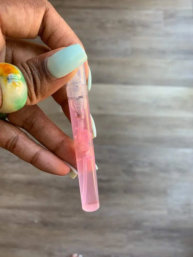 Hand holding pink liquid in a bottle. Hand holding pink liquid in a bottle.