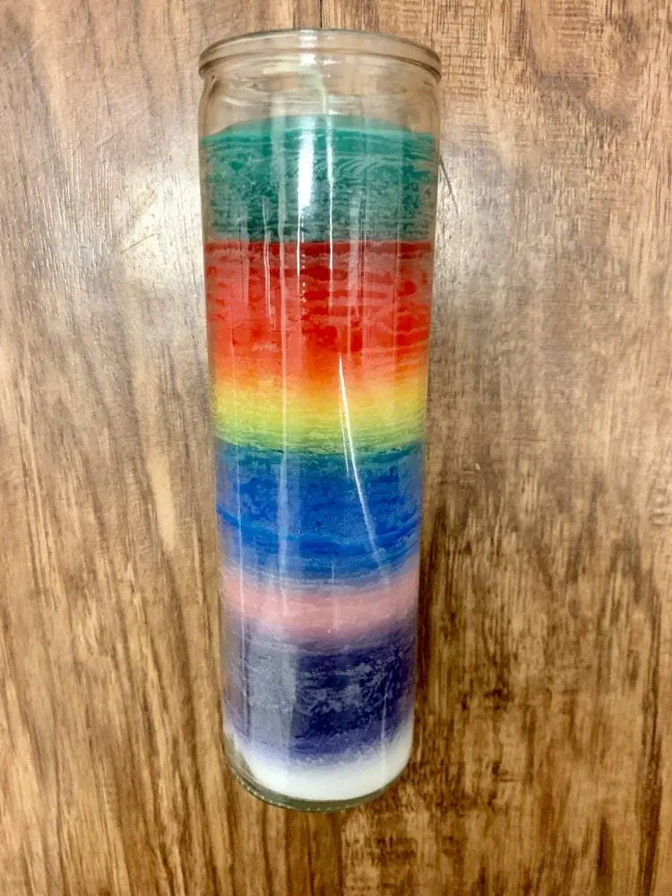 Rainbow layered glass candle on wood. Rainbow layered glass candle on wood.