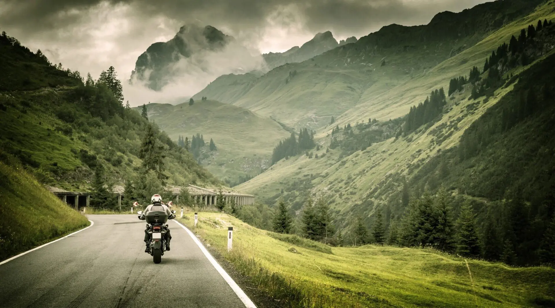 Motorcyclist drives through mountain pass. Motorcyclist drives through mountain pass.