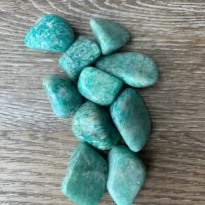Green amazonite tumbled stones on wood.