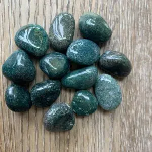 Green moss agate tumbled stones on wood.