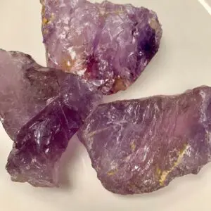 Three rough amethyst crystals on a plate.