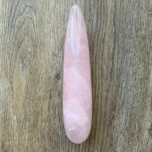 Pink rose quartz crystal on wood.