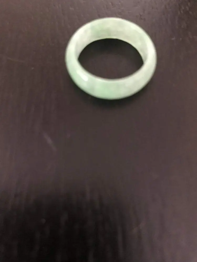 Green jade stone ring on black surface. Green jade stone ring on black surface.