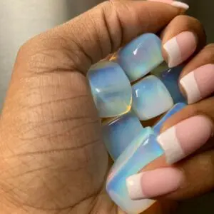 Hand holding iridescent gemstone tumbled stones.