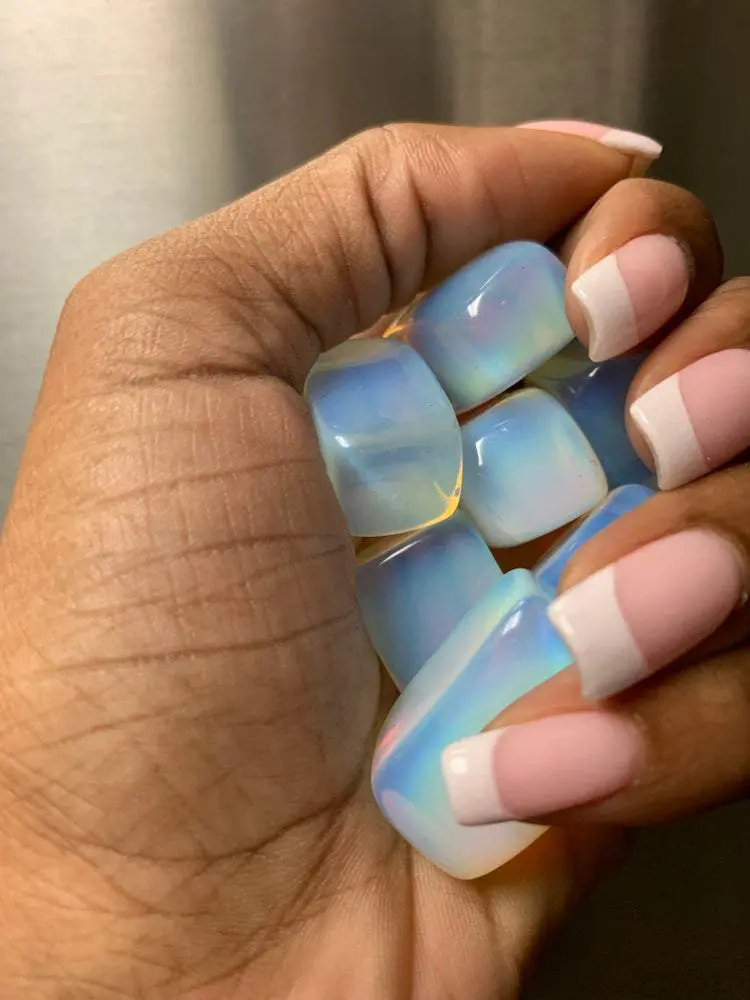 Hand holding iridescent gemstone tumbled stones. Hand holding iridescent gemstone tumbled stones.