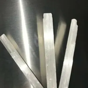 Three white selenite wands on a hand.