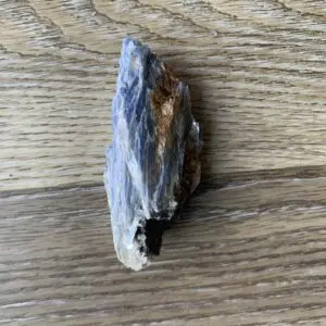 Blue kyanite crystal on woodgrain.