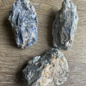 Three blue kyanite crystals on wood.