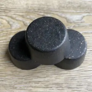 Three round black soap bars on wood.