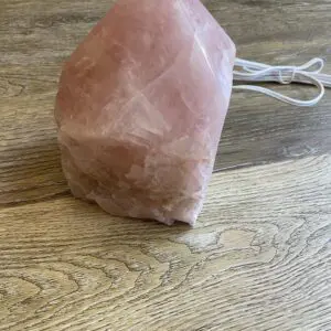 Pink crystal pyramid lamp on wood table.