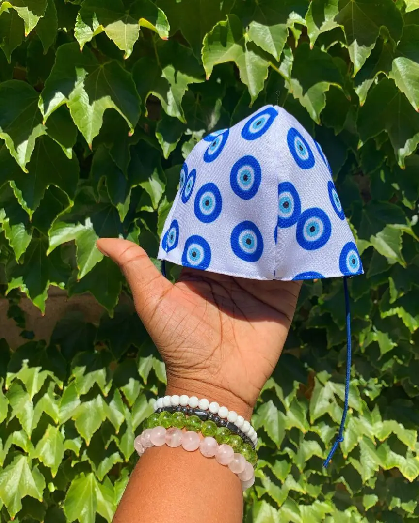 Hand holding evil eye patterned face mask. Hand holding evil eye patterned face mask.