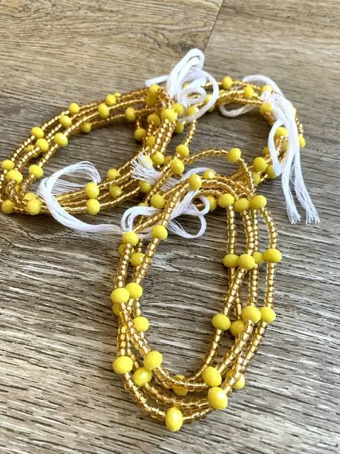 Yellow beaded waist beads with white tassels. Yellow beaded waist beads with white tassels.