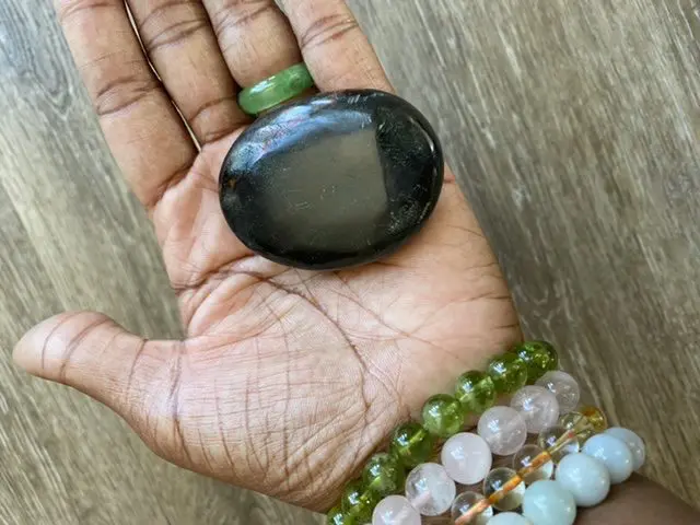 Black obsidian palm stone in hand. Black obsidian palm stone in hand.