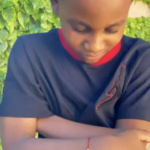 Boy wearing a red string bracelet with evil eye charm.