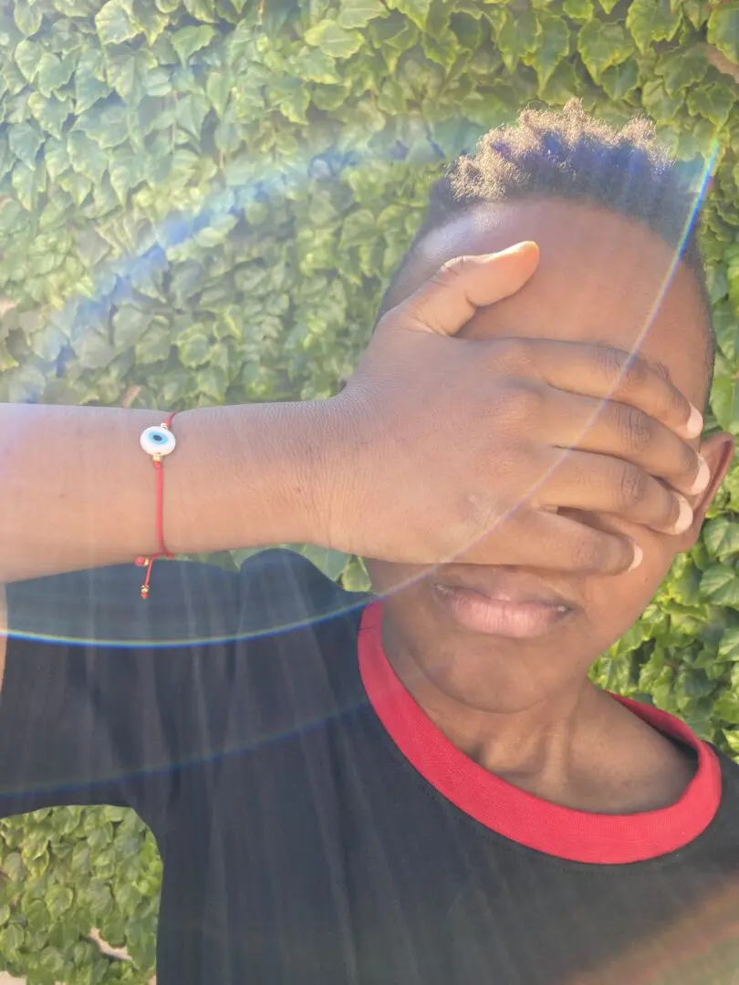 Person with hand over face wearing evil eye bracelet. Person with hand over face wearing evil eye bracelet.