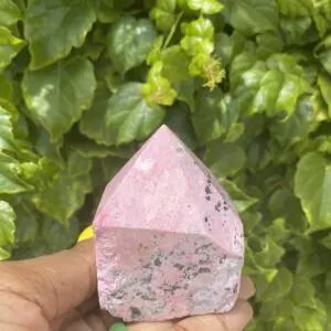Pink Rhodochrosite crystal point in hand.