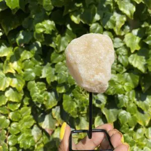 A hand holding a white crystal on a stand.