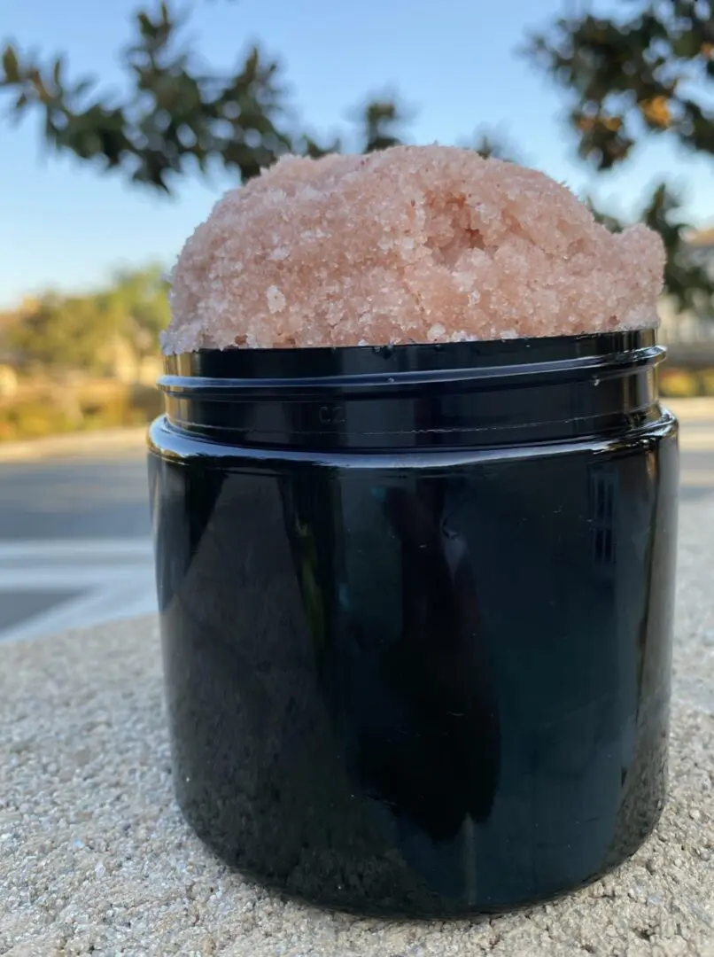 A black container with pink rock on top of it. A black container with pink rock on top of it.