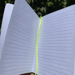 A person holding an open notebook with yellow lines.