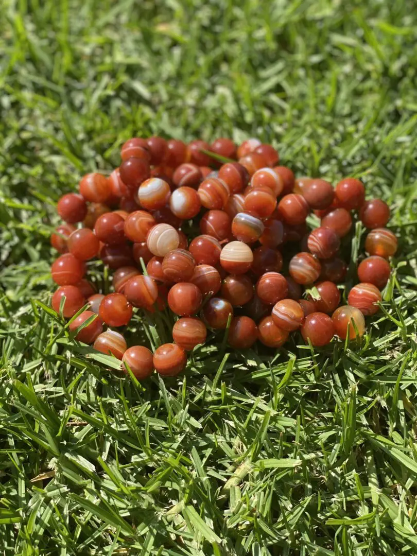 A pile of red beads sitting on top of grass. A pile of red beads sitting on top of grass.