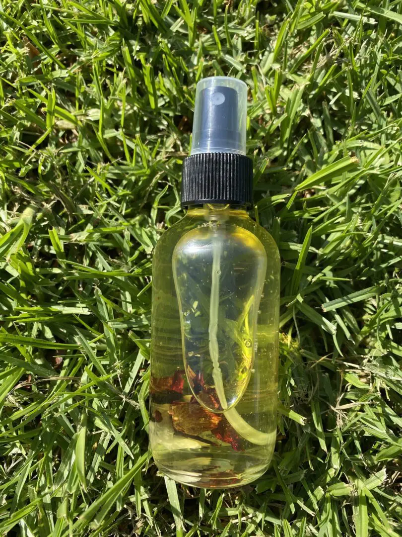 A bottle of oil sitting on top of grass. A bottle of oil sitting on top of grass.