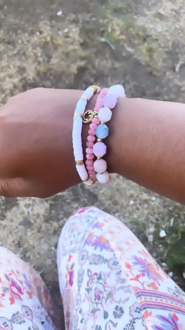 A woman 's hand is holding onto some bracelets A woman 's hand is holding onto some bracelets