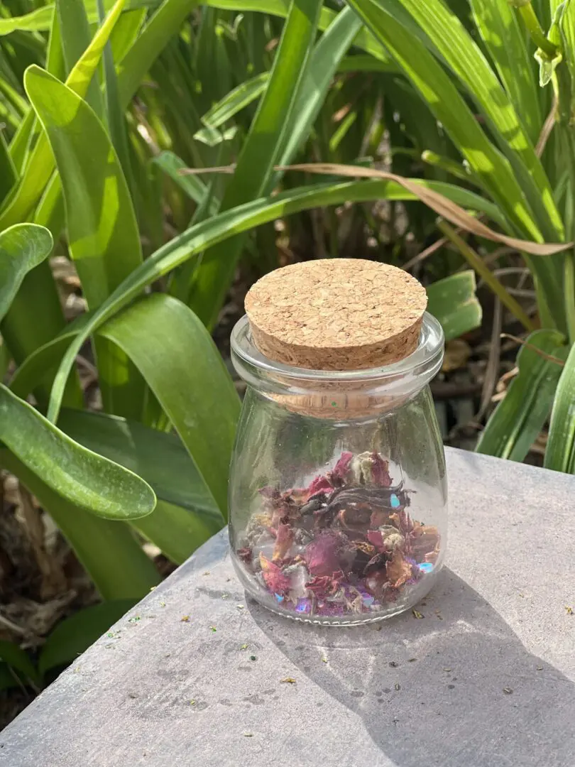 A jar of dried flowers sitting on top of a table. A jar of dried flowers sitting on top of a table.
