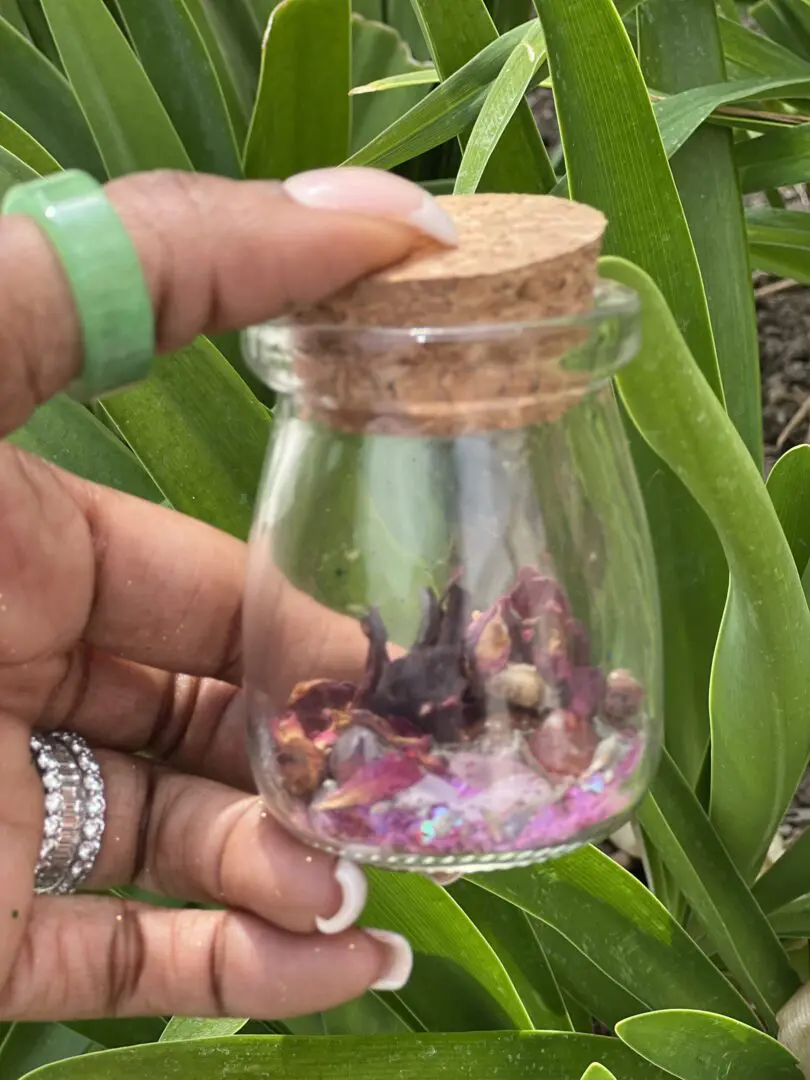 A person holding a jar with some flowers inside of it A person holding a jar with some flowers inside of it