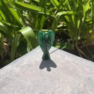 A green glass bird sitting on top of a cement surface.