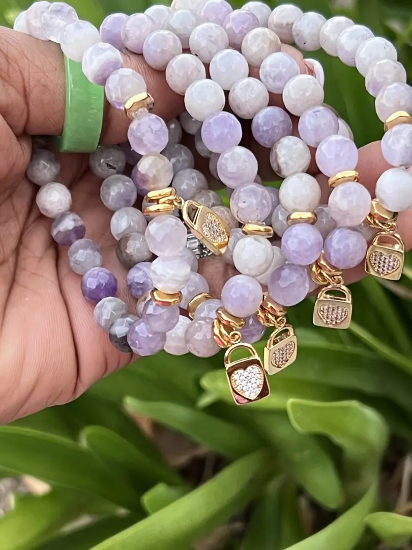 A hand holding onto some bracelets with charms A hand holding onto some bracelets with charms