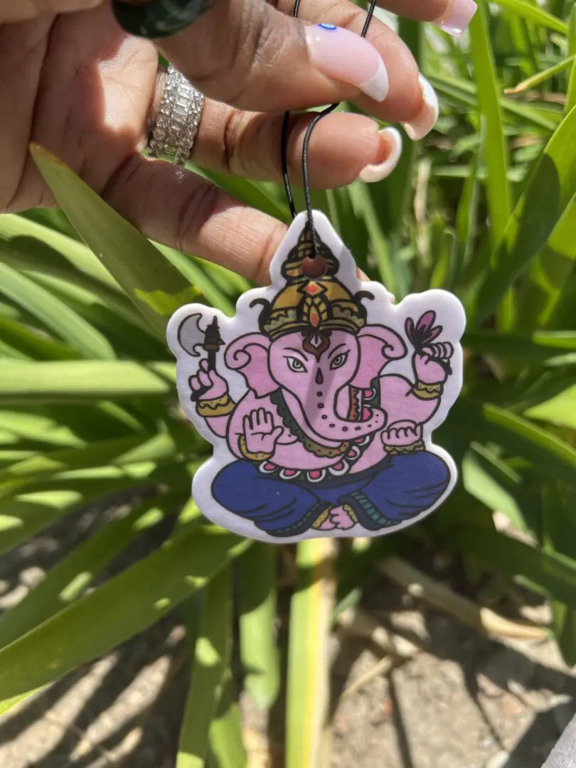 A person holding up an elephant head keychain. A person holding up an elephant head keychain.