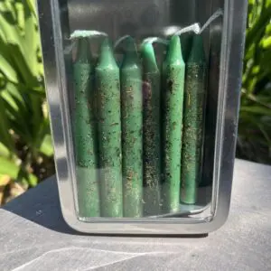 A container of green candles on the ground.