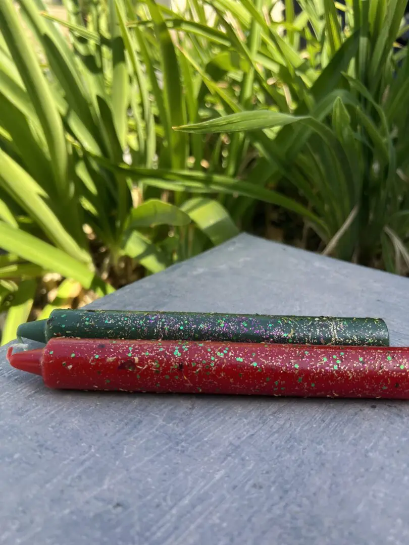 Two candles are sitting on a table outside. Two candles are sitting on a table outside.