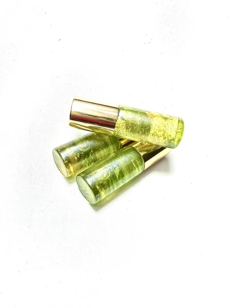 Three green bottles of liquid sitting on top of a table. Three green bottles of liquid sitting on top of a table.