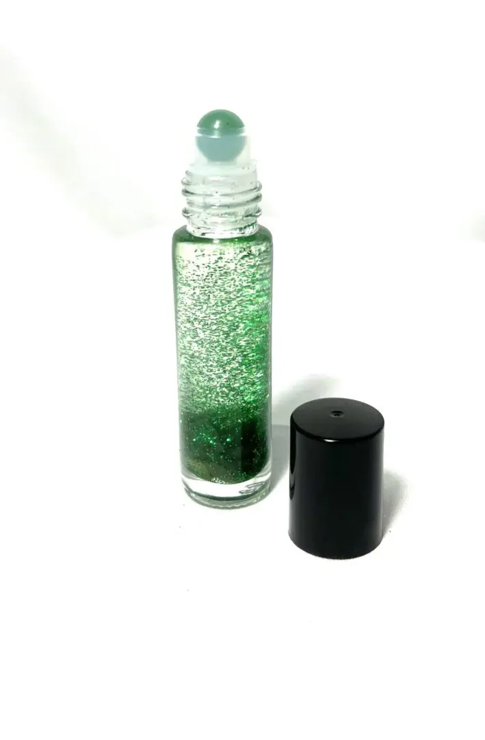 A bottle of green liquid next to a black container. A bottle of green liquid next to a black container.