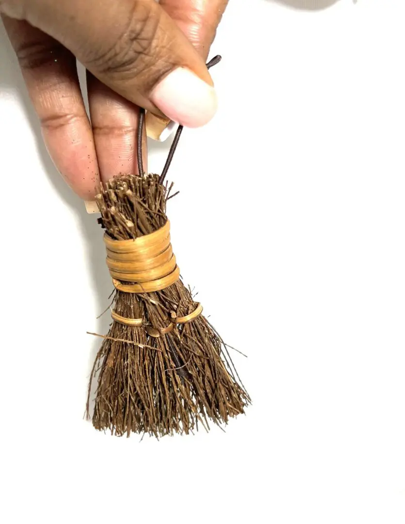 A person holding a small broom in their hand. A person holding a small broom in their hand.