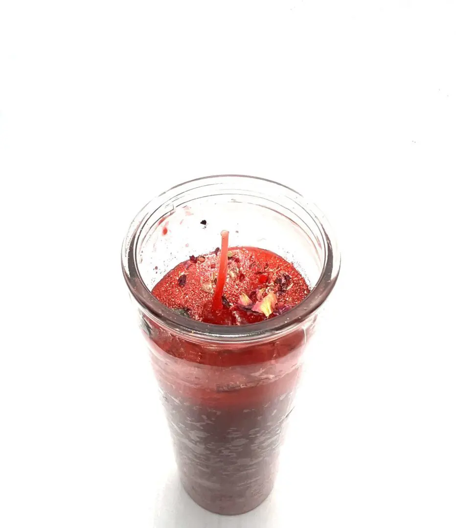 A candle in a glass with red liquid inside. A candle in a glass with red liquid inside.