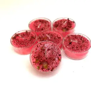 A group of six pink tea lights sitting on top of each other.