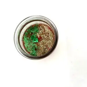 A glass of liquid with green and red substance in it.