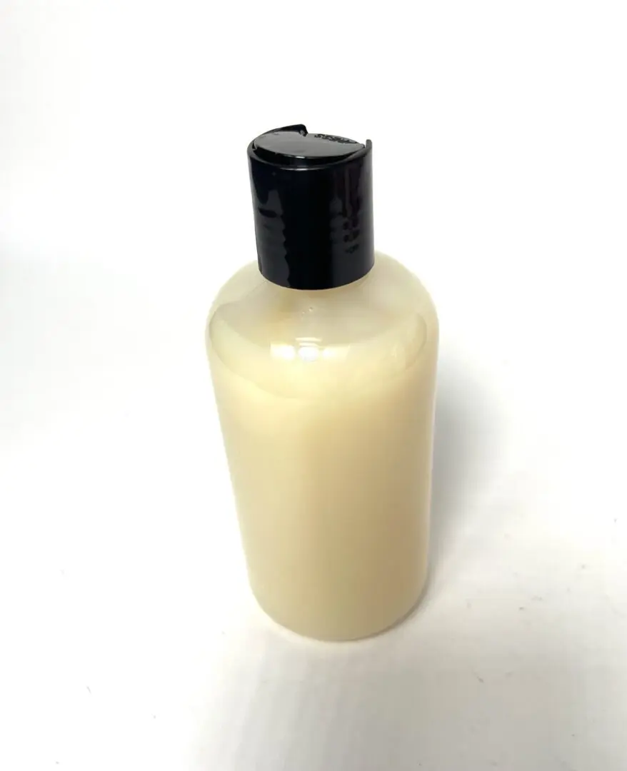 A bottle of lotion sitting on top of a table. A bottle of lotion sitting on top of a table.