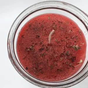 A jar of red liquid with some herbs in it