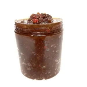 A jar of chocolate spread with nuts on top.
