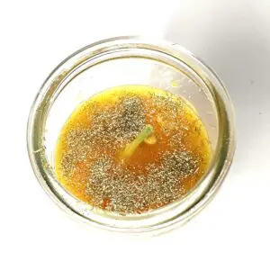A glass of liquid with some kind of seasoning in it