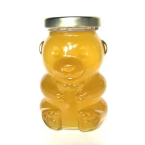 A bear shaped jar of honey with metal lid.