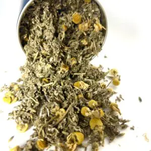 A metal container filled with lots of dried herbs.