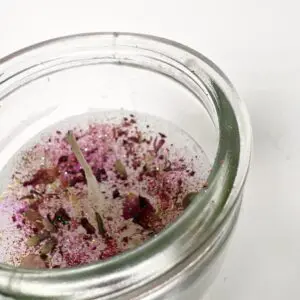 A jar candle with dried flowers embedded in the wax.