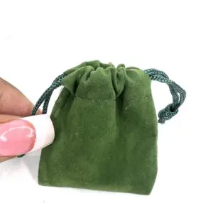 Small green velvet drawstring pouch held by hand.